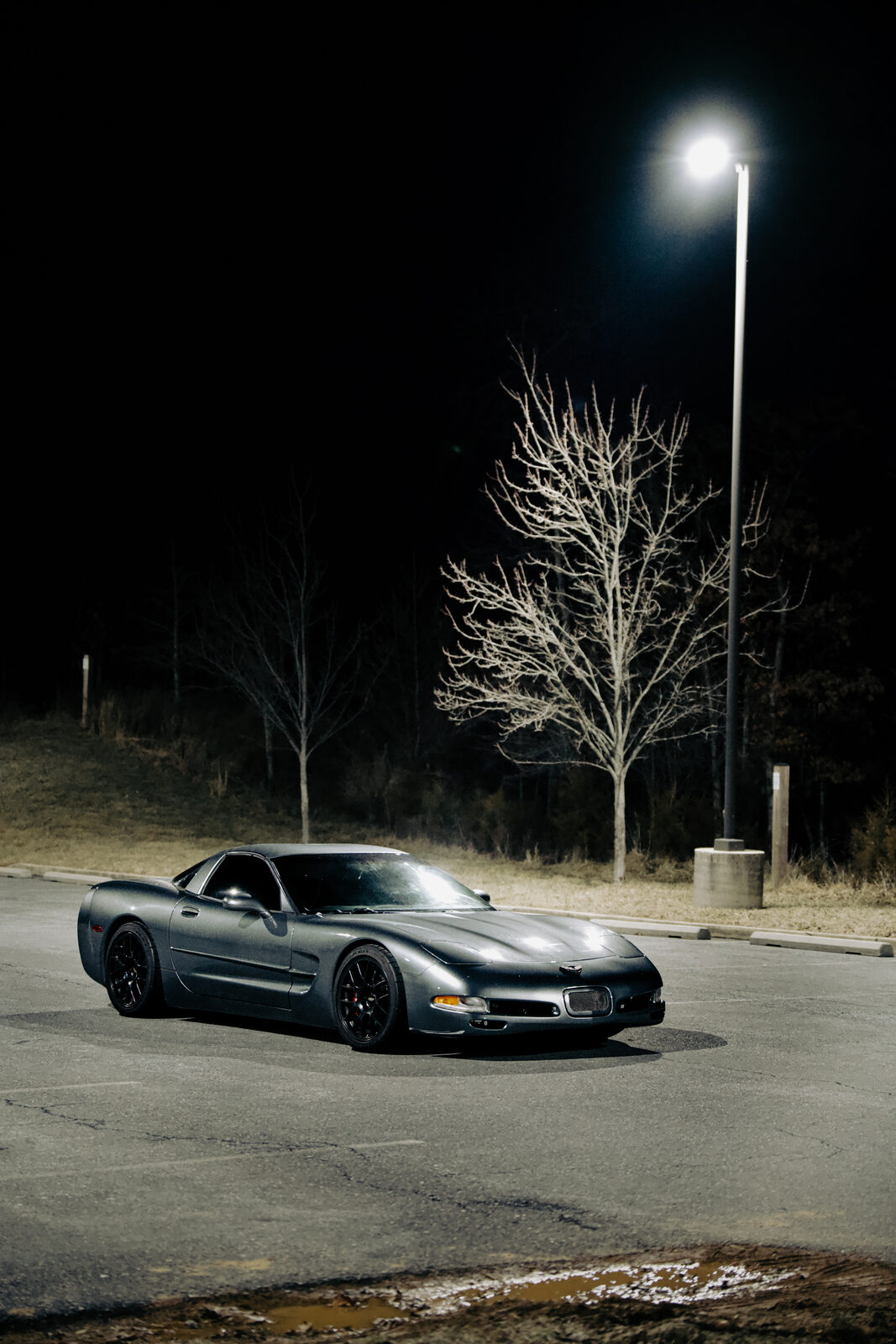 A grey Corvette C5, front three-quarter view at night.