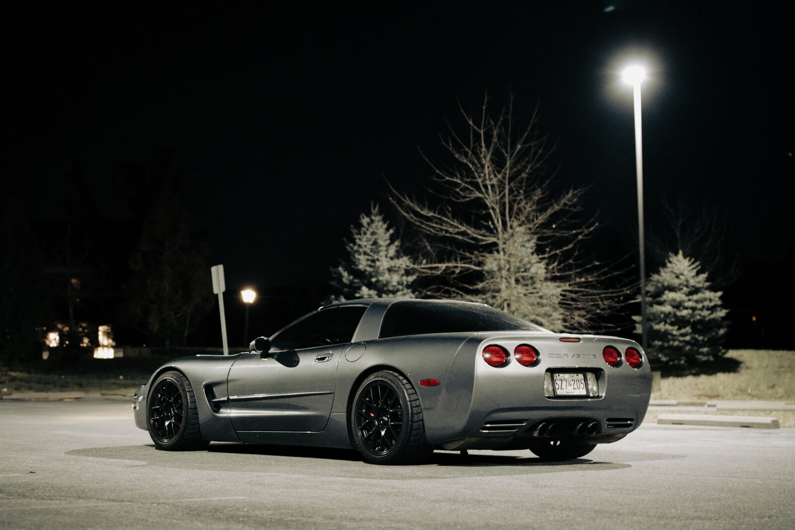 A grey Corvette C5, rear three-quarter view at night.