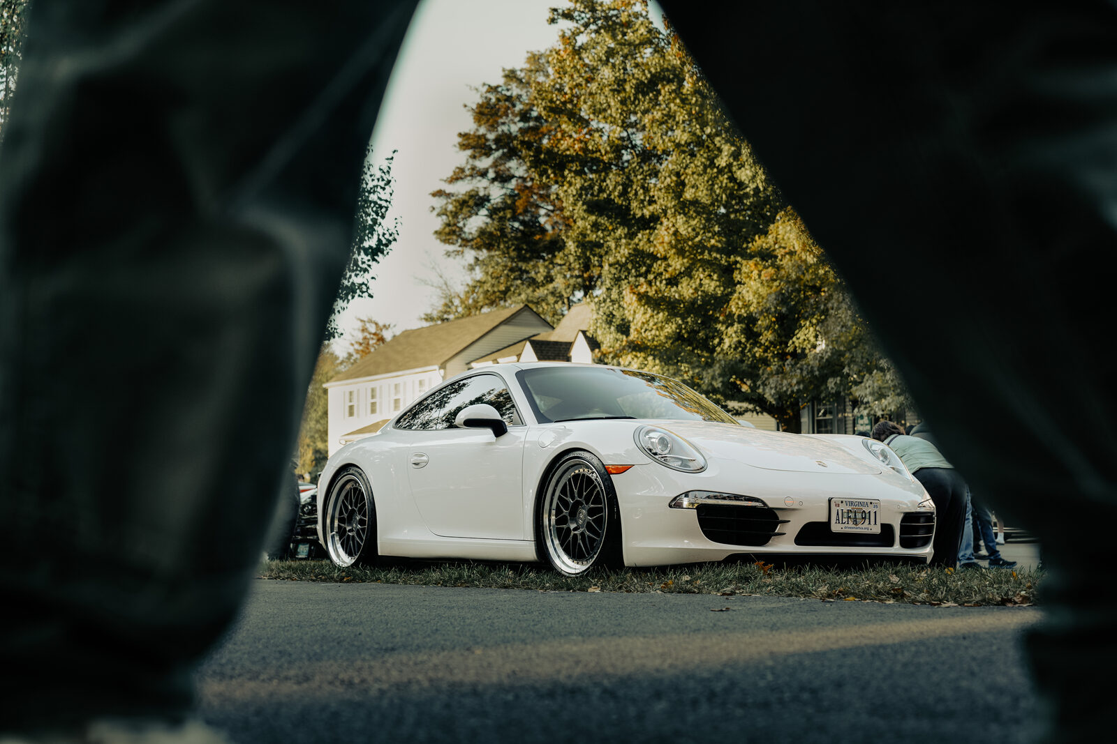 A white Porsche 911, shot framed through the foreground.