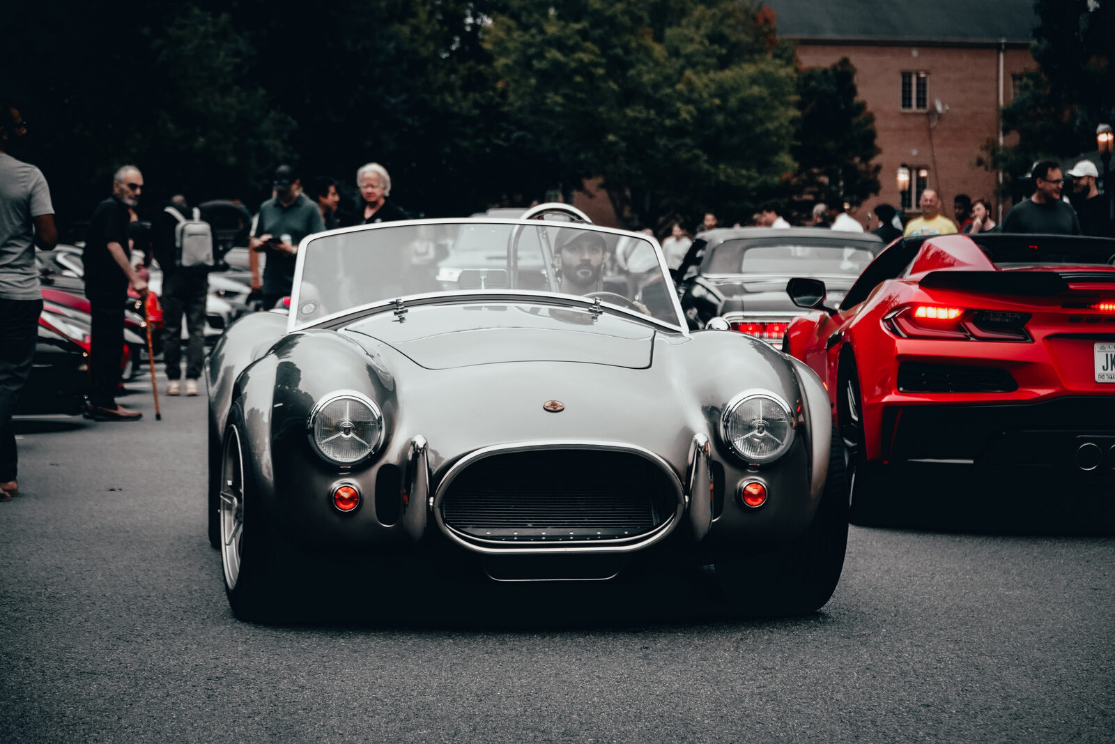 A Shelby Cobra replica among other cars at a car meet.