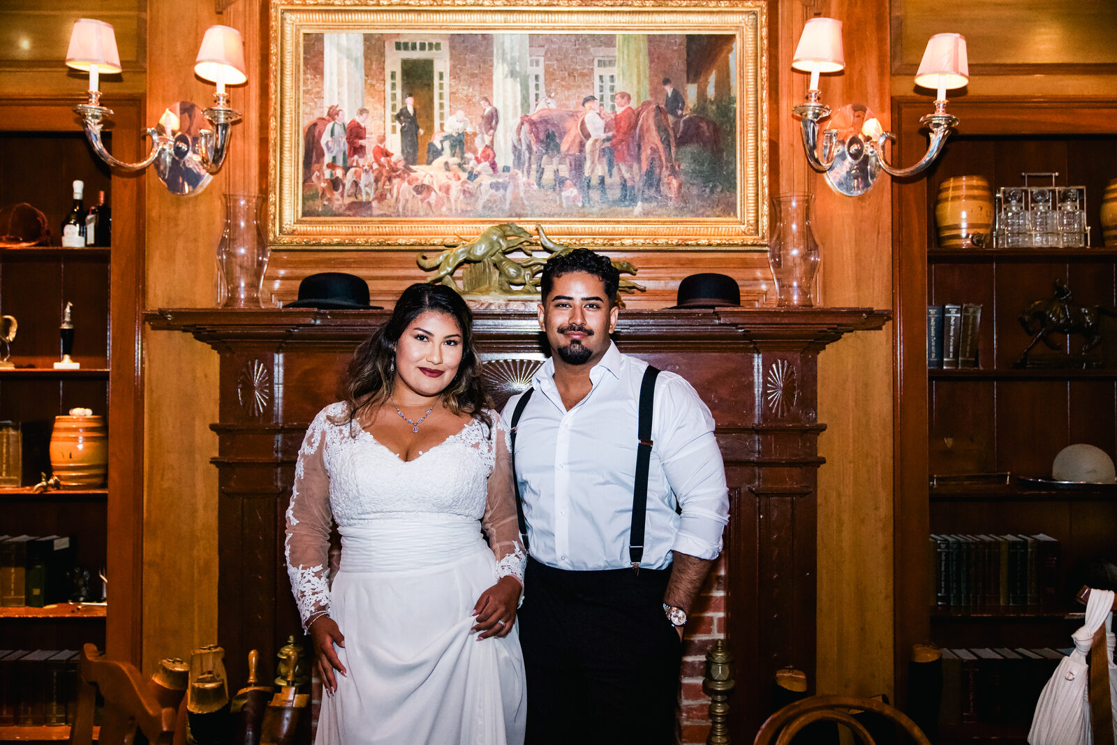 A wedding couple portrait standing by a wood-paneled fireplace.