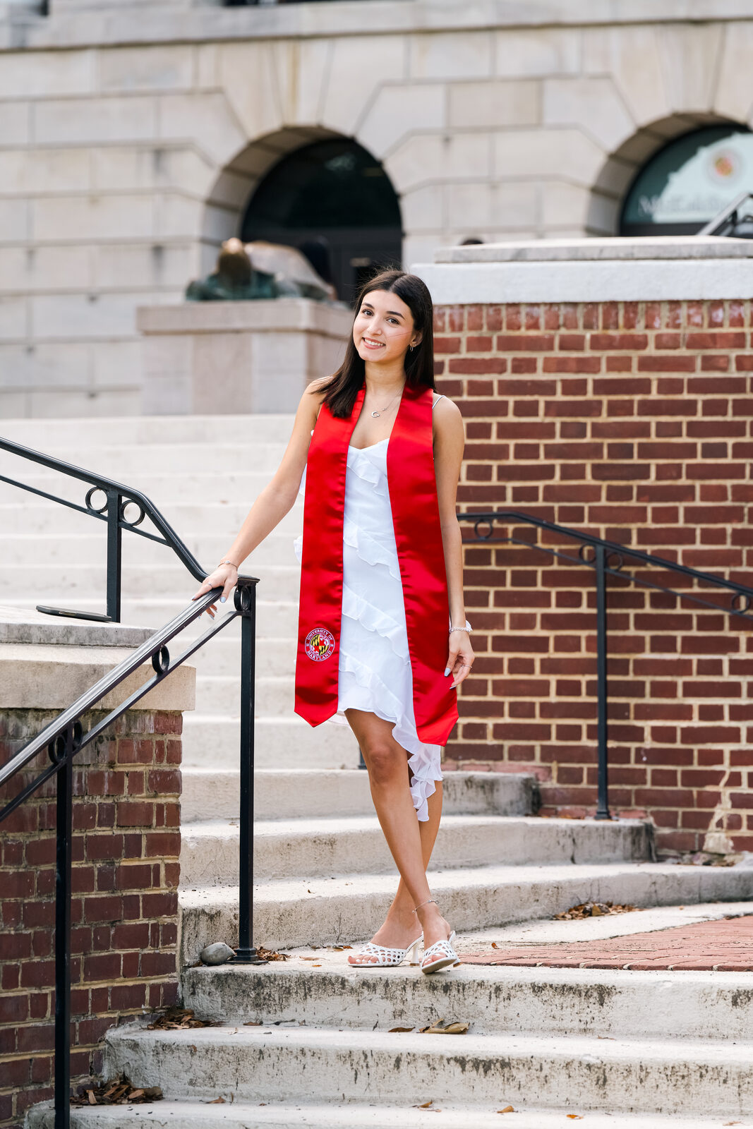 A graduate standing on brick steps on campus.