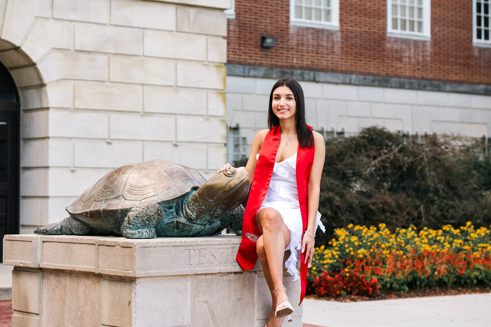 A graduate posing beside the Testudo turtle statue at a different angle.