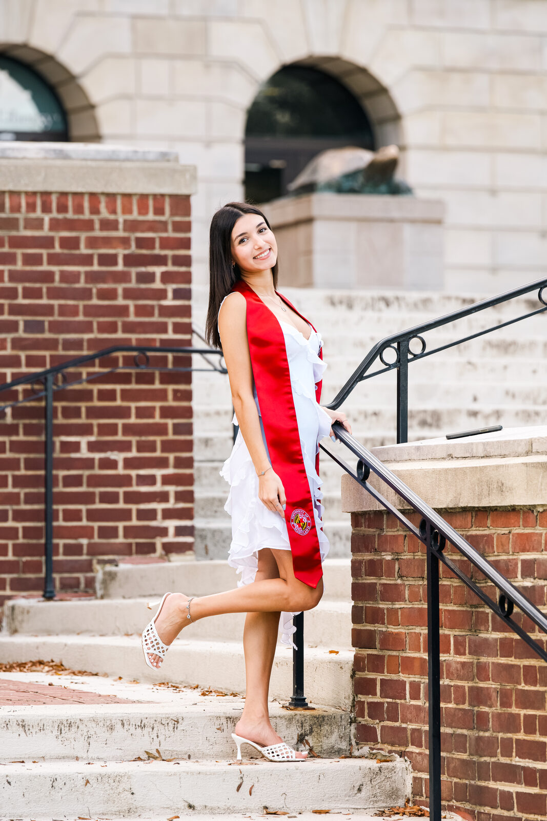 A graduate posing on campus steps, side view.