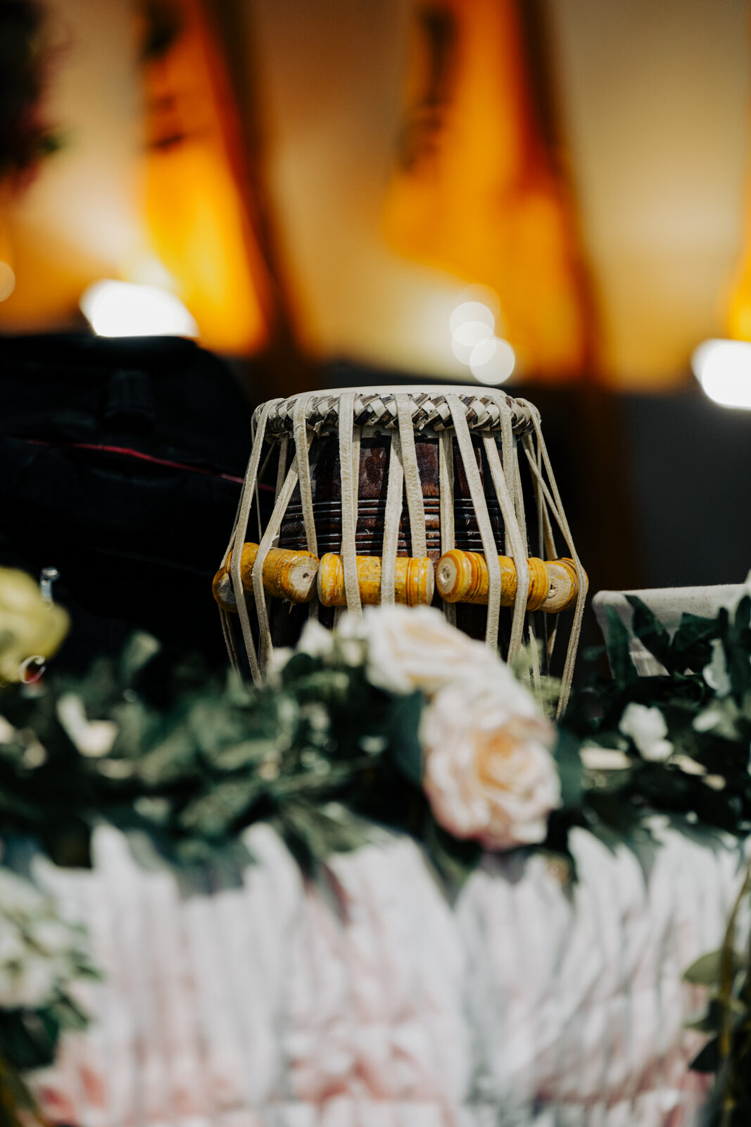 A close-up detail shot of a tabla drum framed by flowers.