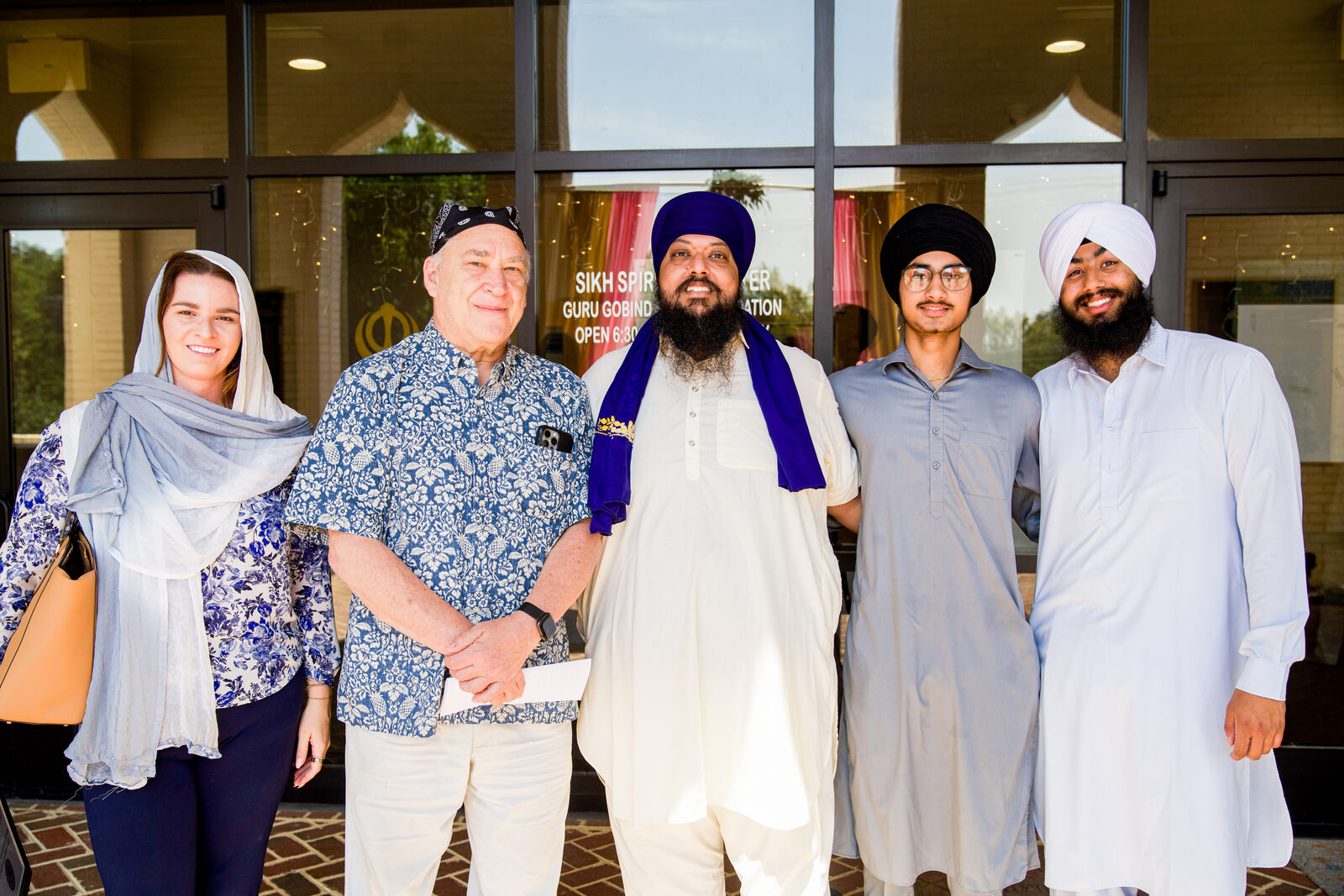 A group portrait of five people at the gurdwara entrance.