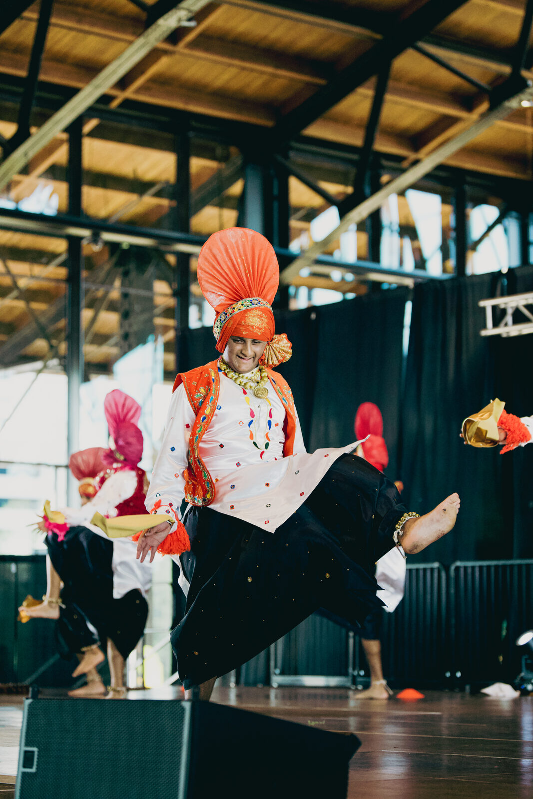 A Bhangra performer in a red turban holding a flag.