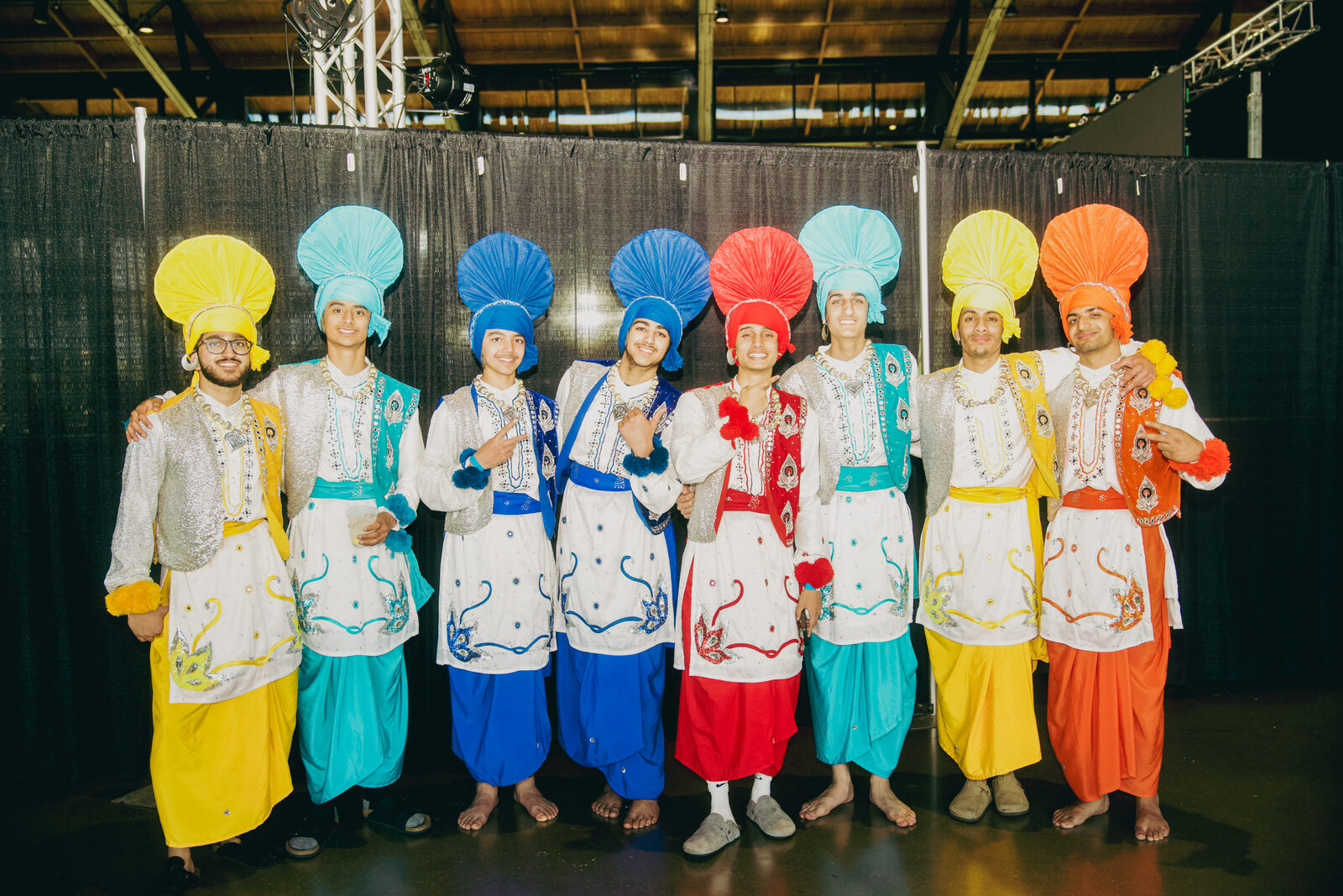 A dance team posing together backstage in colorful costumes.