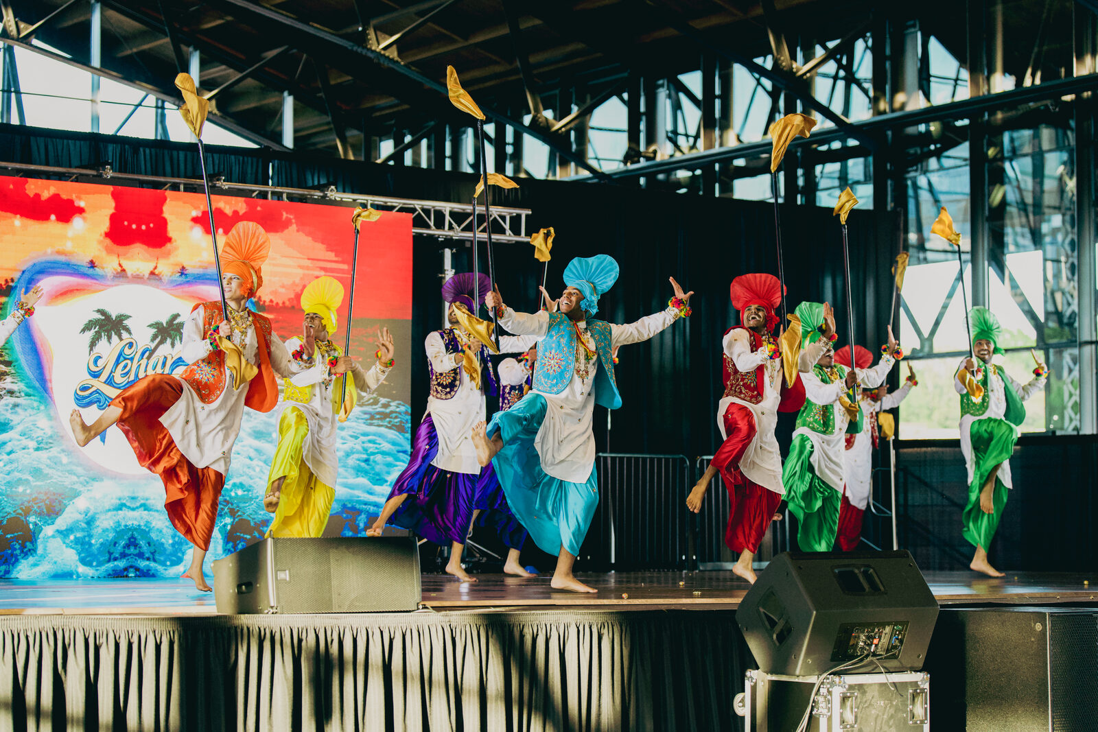 A Bhangra dance team performing on the main stage, colorful turbans and flags in motion.