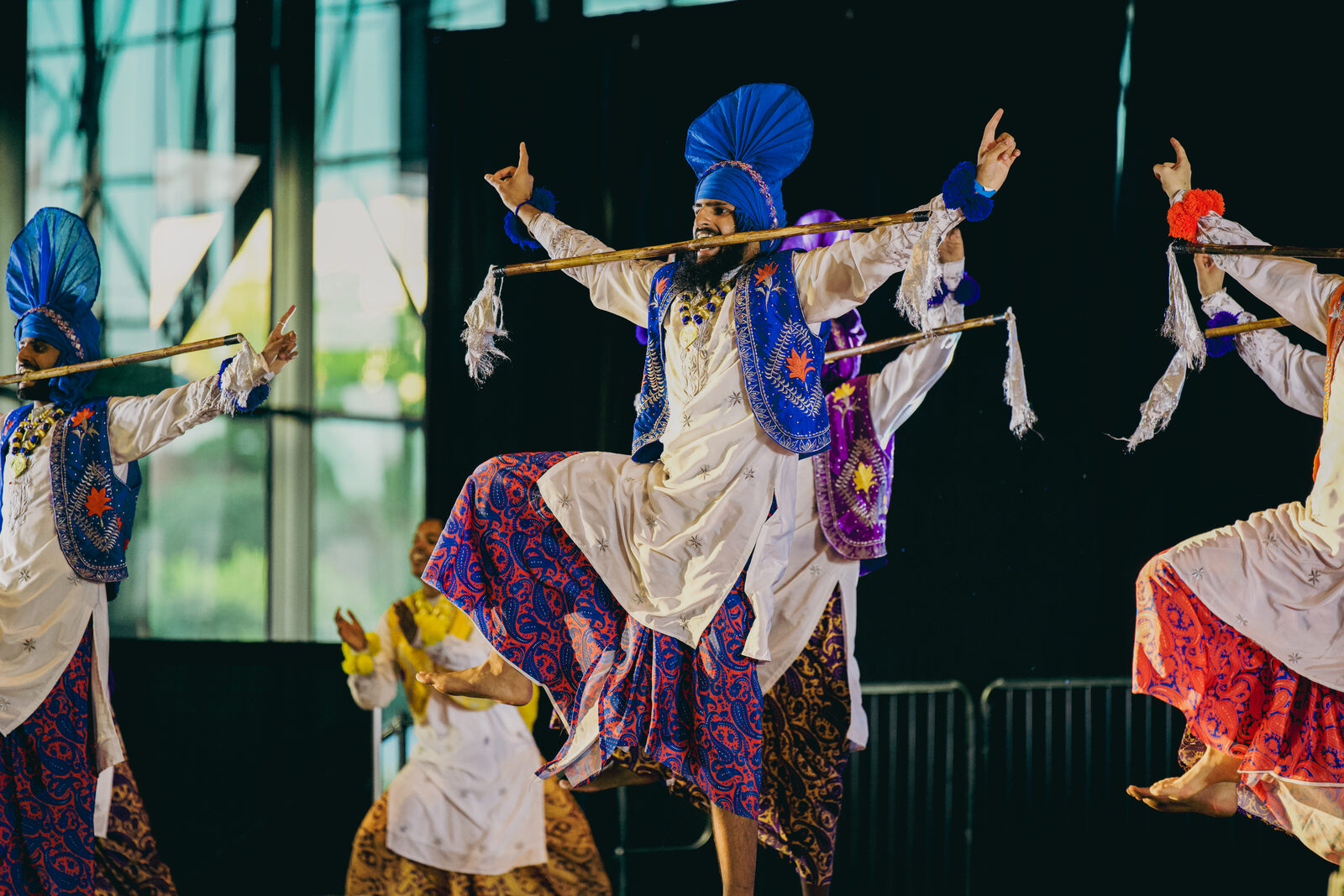 A solo Bhangra performer mid-jump against a purple-lit backdrop.