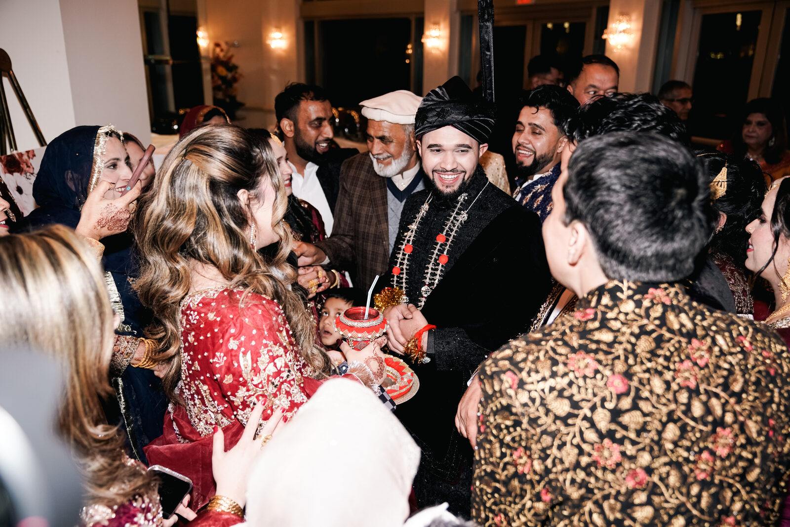 Wedding reception crowd surrounding the groom during the garland ceremony.