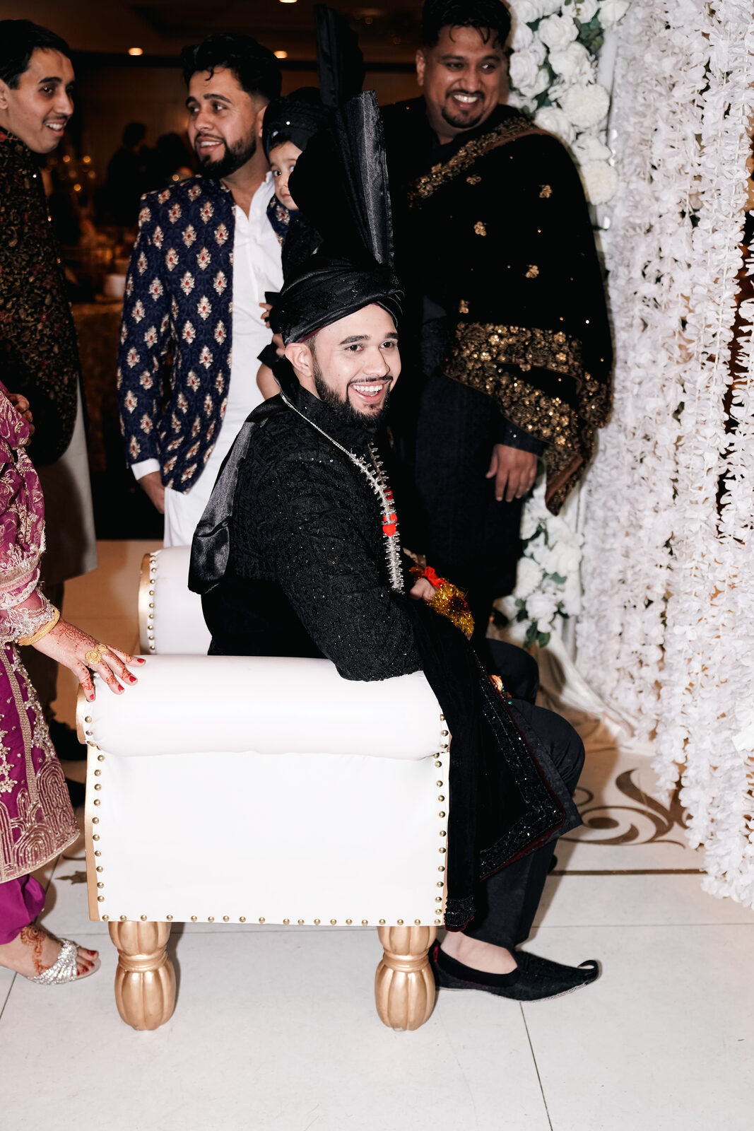 A candid photo of the groom and friends under a floral arch.