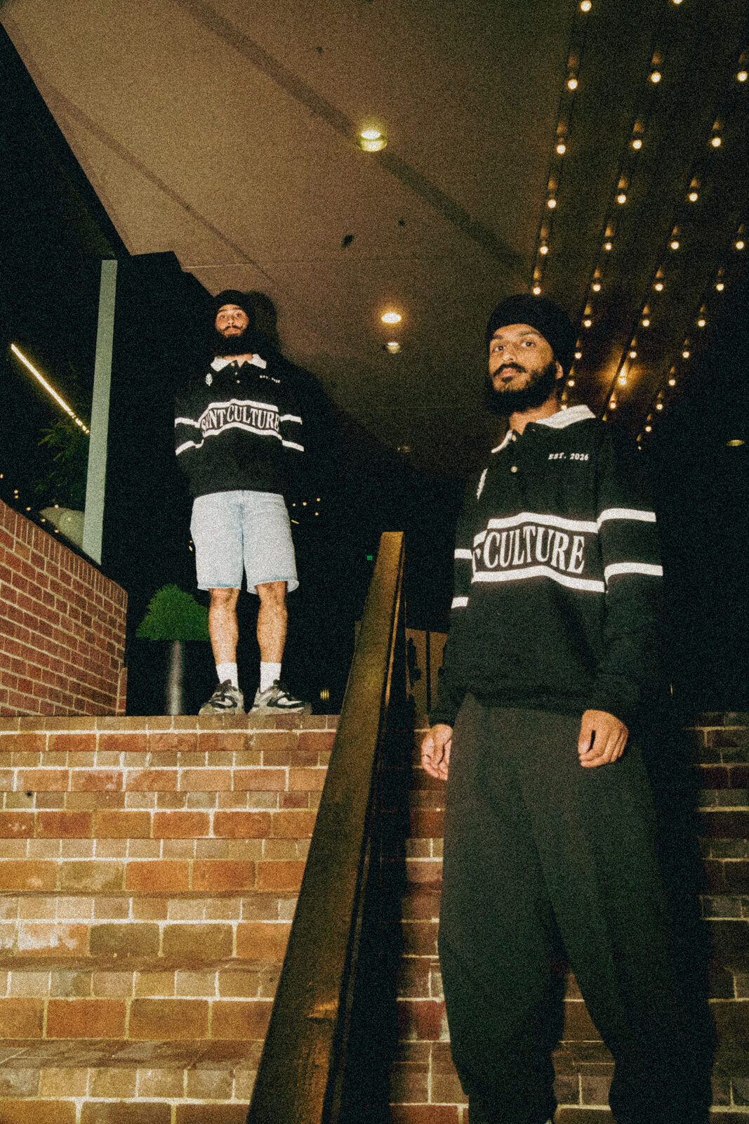 A streetwear campaign shot on brick stairs at night.