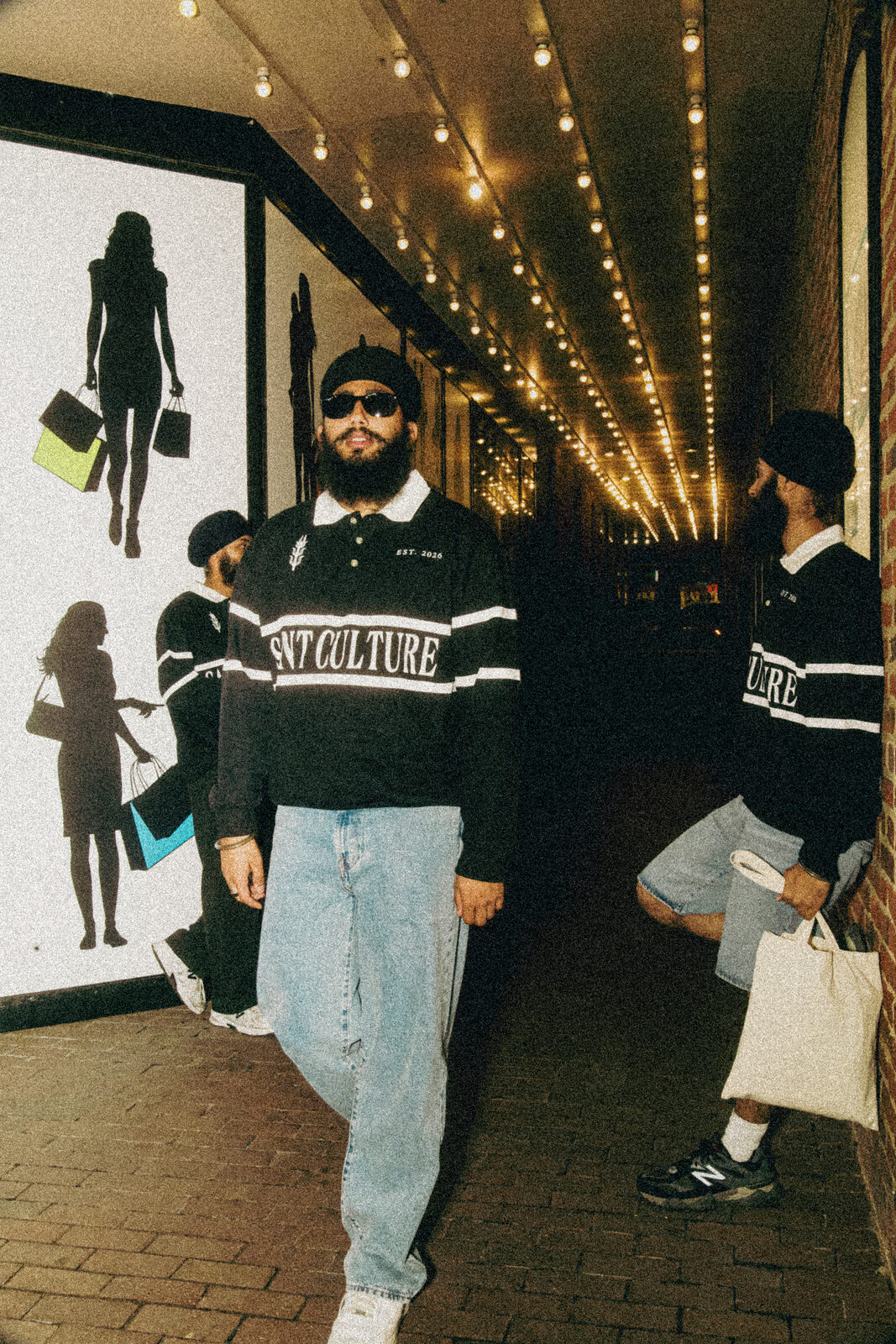 A streetwear campaign shot walking through a string-lit alley.