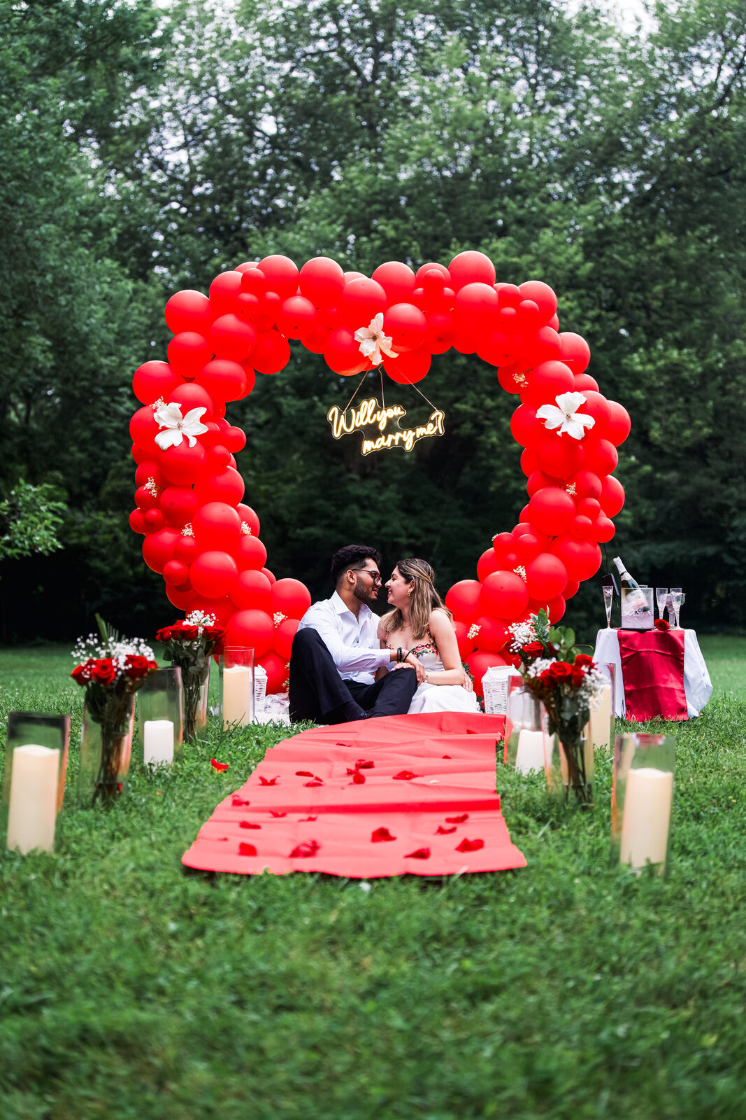 The newly engaged couple sitting together under the balloon arch afterward.
